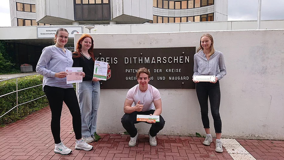 Schülerinnen und Schüler präsentieren vor dem Kreishaus in Heide die Auszeichnung zur Zukunftsschule.