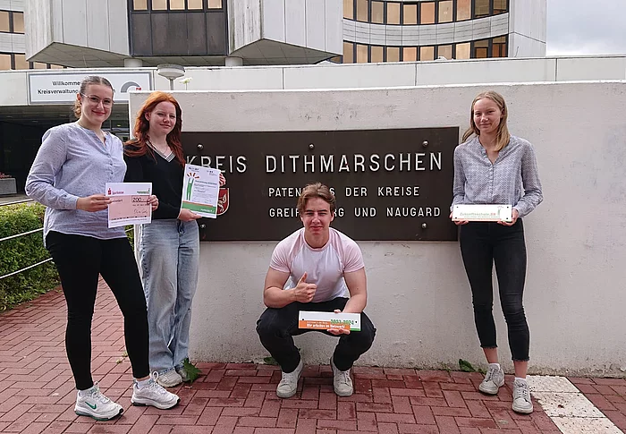 Schülerinnen und Schüler präsentieren vor dem Kreishaus in Heide die Auszeichnung zur Zukunftsschule.