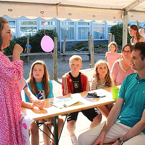 Sommerfest für Fünftklässler. Schüler, Eltern und Lehrer sitzen zusammen auf dem Schulhof.